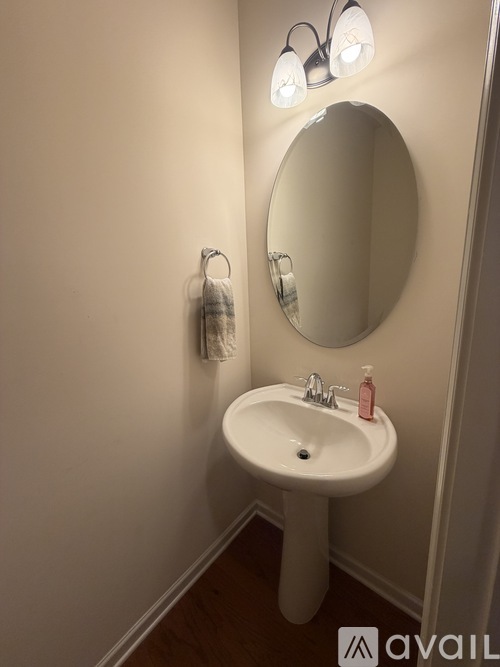 A white pedestal sink with a round mirror above it.