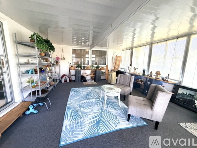 A living room with a blue and white patterned rug, a white table, and a blue chair.