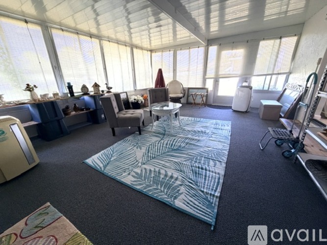 A living room with a large rug and a glass wall.