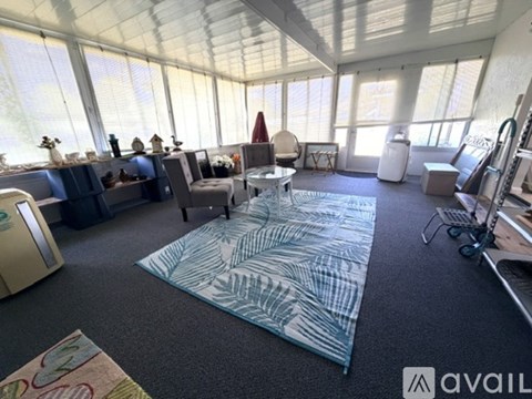 A living room with a large rug and a glass wall.