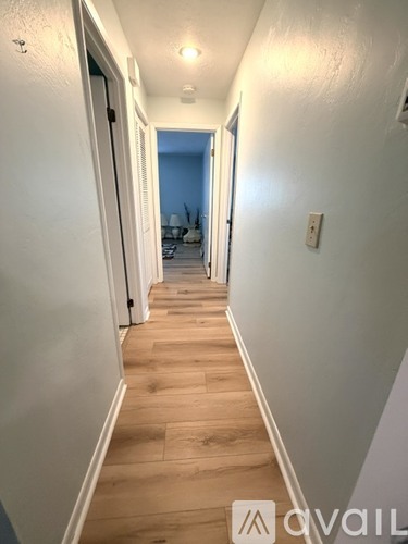 A hallway with wooden floors and white walls.