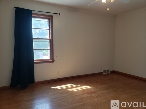 A bedroom with a bed, a window with curtains, and two pictures on the wall.