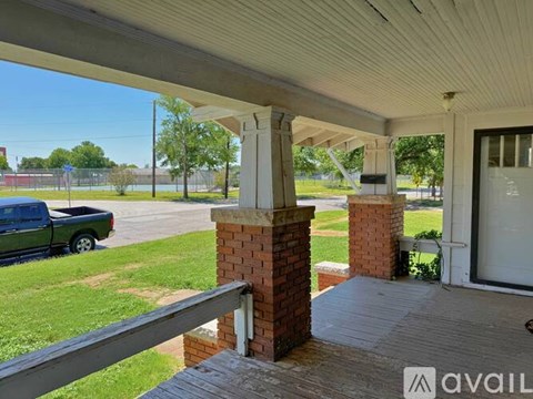 A porch with a brick column and a truck in the background.