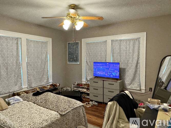 A bedroom with a bed, dresser, and a ceiling fan.