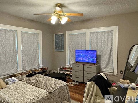 A bedroom with a bed, dresser, and a ceiling fan.