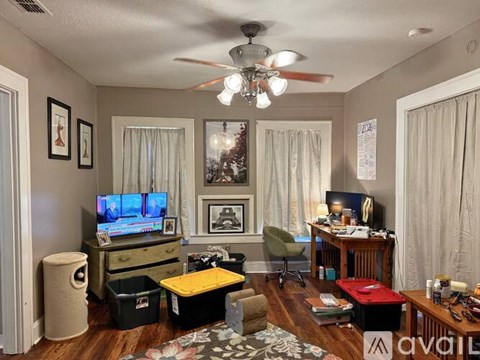 A living room with a television, a chair, and a fan.