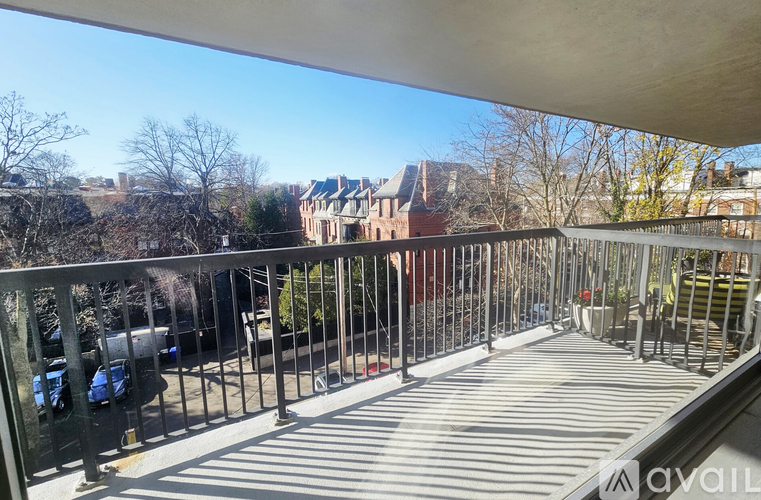 A balcony with a metal railing and a view of buildings in the distance.