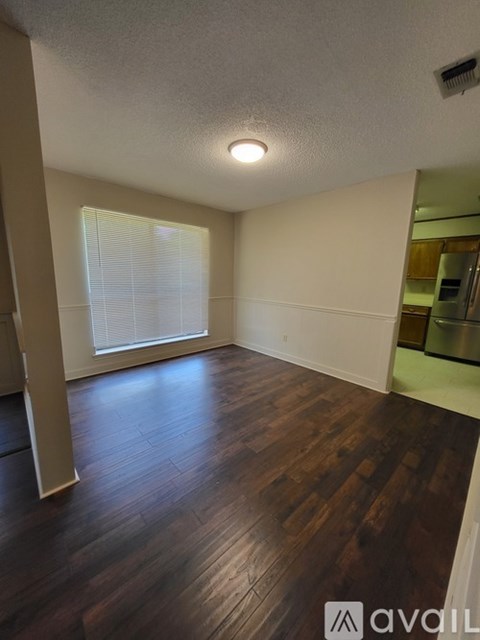 A room with wooden floors and a window with blinds.