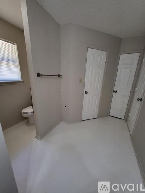 A bathroom with a toilet, a bathtub, and two doors.