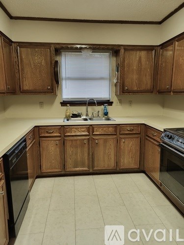A kitchen with wooden cabinets and a black dishwasher.