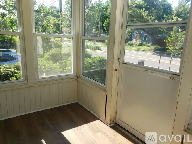 A room with a wooden floor and a view of a street through the windows.