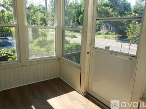 A room with a wooden floor and a view of a street through the windows.