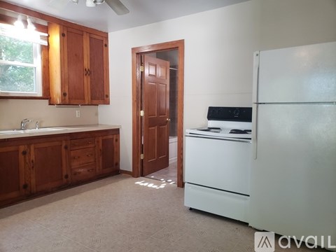 A kitchen with a white fridge and wooden cabinets.