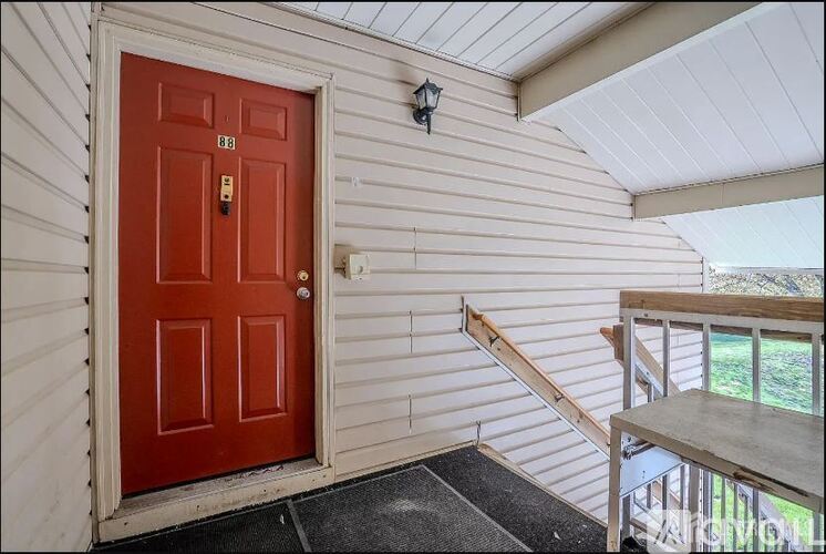 A red door is on the left side of a white wall.
