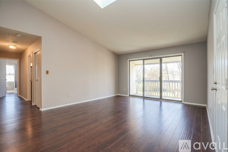 A spacious room with wooden floors and a skylight.