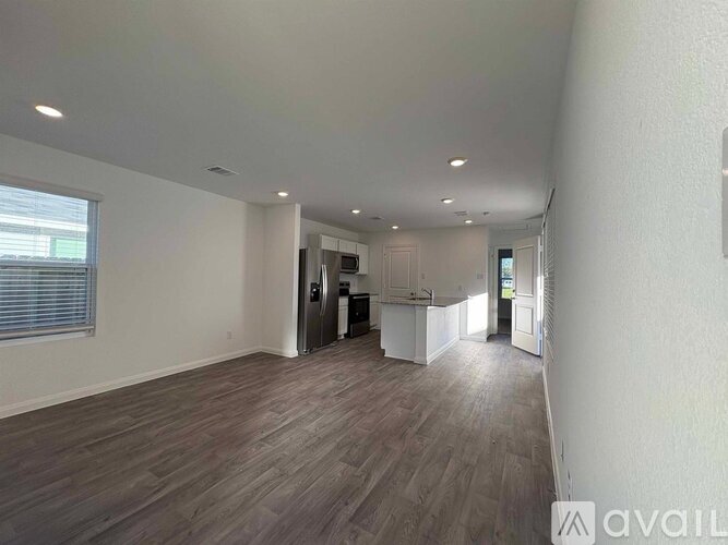 A spacious room with wooden flooring and white walls.