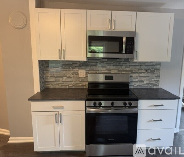 A kitchen with white cabinets and a black countertop.