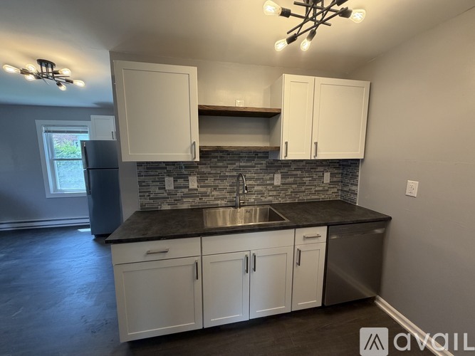 A kitchen with white cabinets and a stone backsplash.