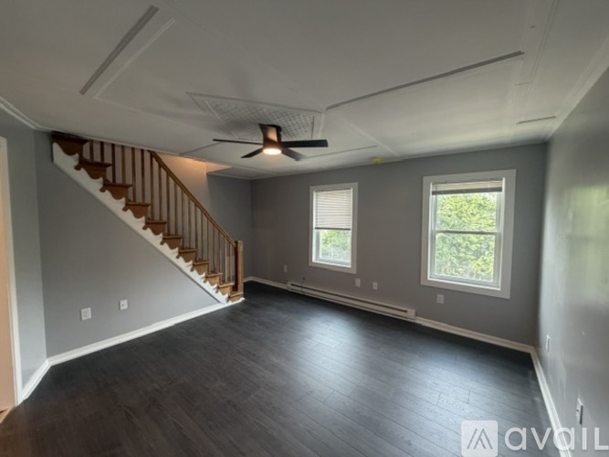 A spacious room with a staircase and a ceiling fan.
