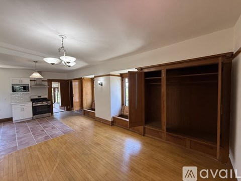 A spacious room with wooden floors and a kitchen area with a stove and oven.