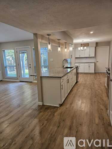 A kitchen with wooden floors and white cabinets is available for rent.