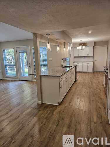 A kitchen with wooden floors and white cabinets is available for rent.