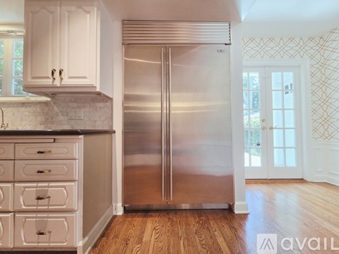 A kitchen with a stainless steel refrigerator and wooden floors.