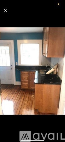 A kitchen with wooden floors and a black countertop.