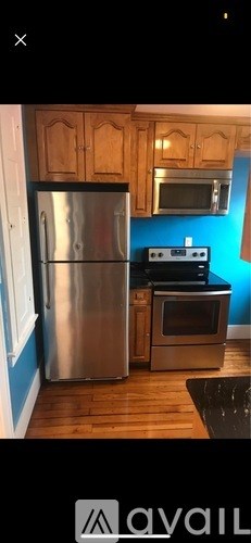 A kitchen with wooden cabinets and a stainless steel refrigerator.