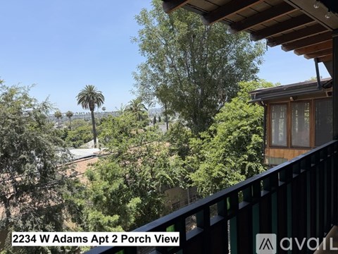 A porch view of a house with trees and a clear sky in the background.