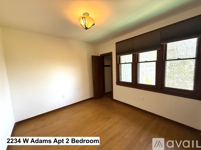 A bedroom with a wooden floor and a window with blinds.
