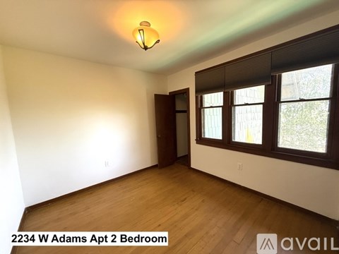 A bedroom with a wooden floor and a window with blinds.