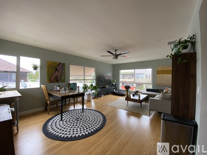 A living room with a dining table and chairs, a couch, a rug, and a ceiling fan.