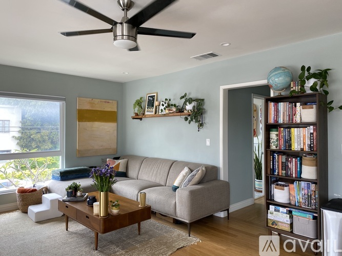 A living room with a beige sofa, a wooden coffee table, and a ceiling fan.