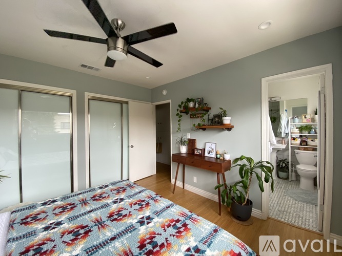 A bedroom with a bed, a ceiling fan, and a mirror.