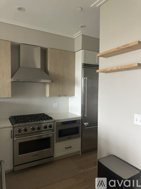 A modern kitchen with stainless steel appliances and wooden shelves.