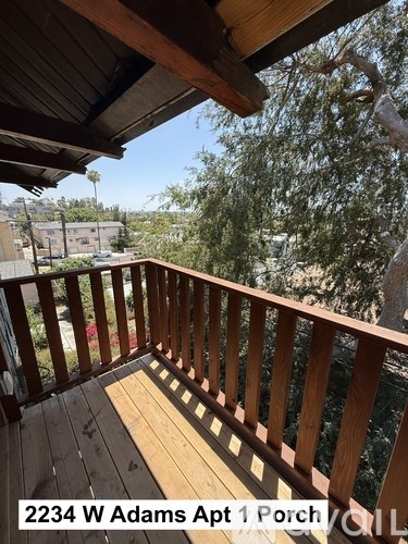 A wooden deck with a view of a street and trees.