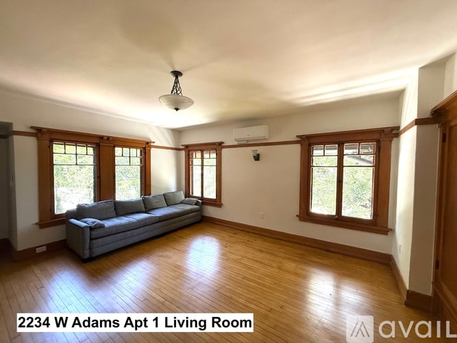 A living room with a grey couch and wooden floors.