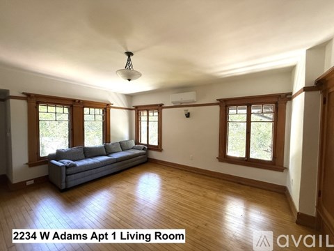 A living room with a grey couch and wooden floors.