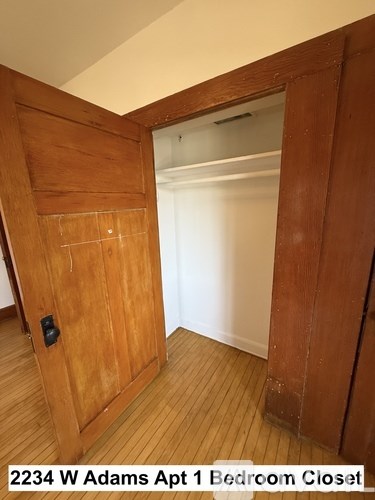 A bedroom closet with a door open to a white room.
