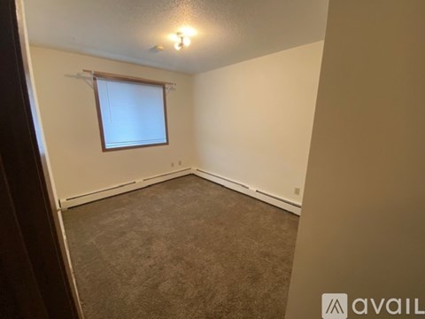 A room with a carpeted floor and a window with blinds.