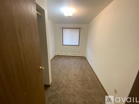 A room with a carpeted floor, a door, and a window with blinds.
