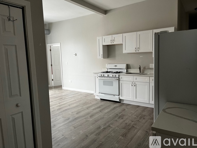 A kitchen with white cabinets and a wooden floor.