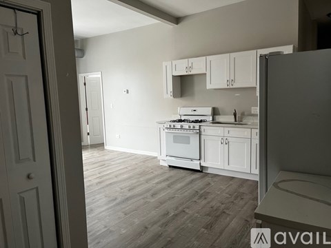 A kitchen with white cabinets and a wooden floor.