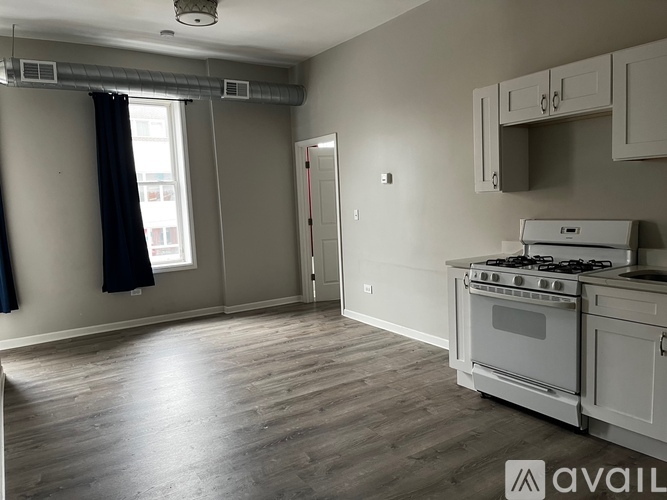 A kitchen with a stove and oven, and a window with a black curtain.