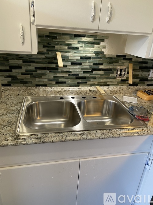A kitchen with a granite countertop and a double sink.