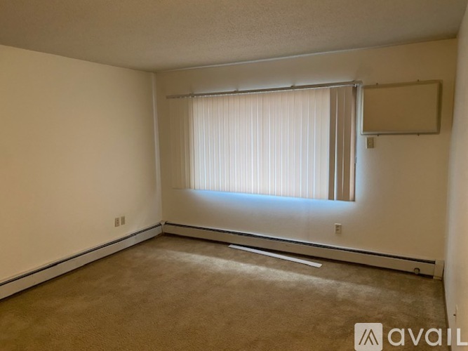 A room with a carpeted floor and a window with blinds.