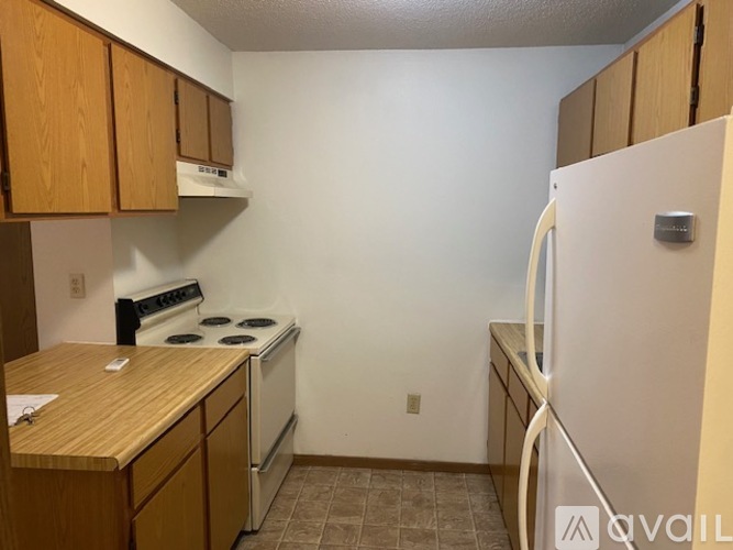 A kitchen with a white refrigerator, wooden cabinets, and a white stove top oven.