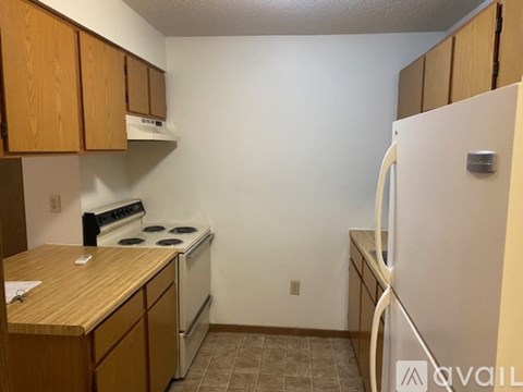 A kitchen with a white refrigerator, wooden cabinets, and a white stove top oven.