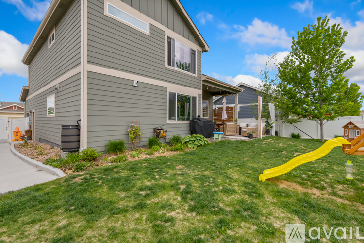 A house with a grey exterior and a yellow slide in the yard.